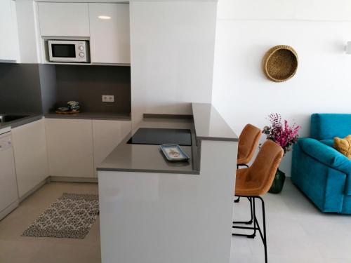 a kitchen with white cabinets and a blue couch at Edificio Calpemar in Calpe