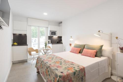 a white bedroom with a bed and a kitchen at Apartments-OILAN11 - Estudios en primera línea de playa PEDREGALEJO in Málaga