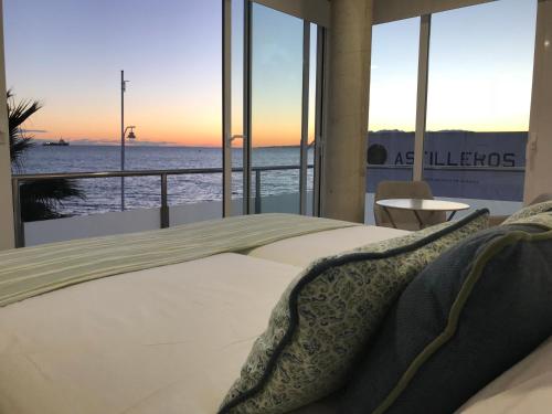 a bedroom with a bed with a view of the ocean at Apartments-OILAN11 - Estudios en primera línea de playa PEDREGALEJO in Málaga