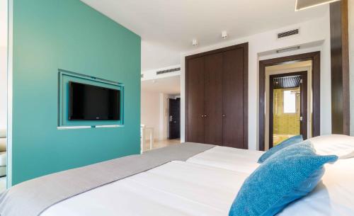a bedroom with a large bed with a blue wall at Suittes Hotel in Algeciras