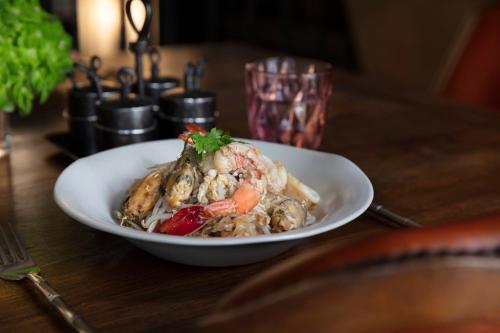 a white plate of food on a wooden table at The Siam in Bangkok