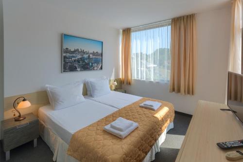 a hotel room with a bed and a television at Hotel Odyssey Sozopol in Sozopol