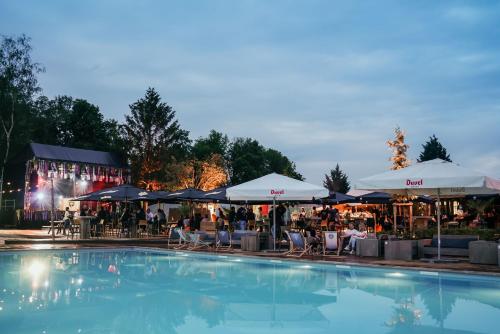 a swimming pool with tables and chairs and umbrellas at Green Fields - Durbuy in Durbuy