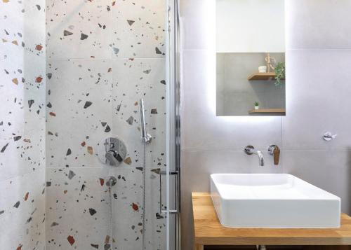 a bathroom with a white sink and a shower at Cove Suites Apartment in Iraklitsa