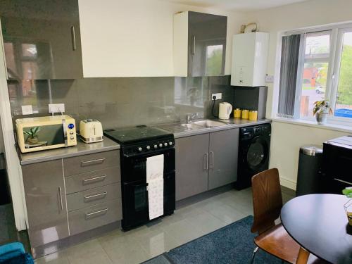 a kitchen with a sink and a stove top oven at Modern & Cosy 2-Bed Apartment Near NEC, Airport & JLR! in Birmingham