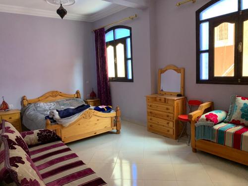 a bedroom with two beds and a dresser and a mirror at Dar Amallay in Tamraght Oufella