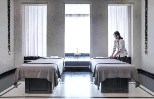 a woman standing between two beds in a room at The Siam in Bangkok