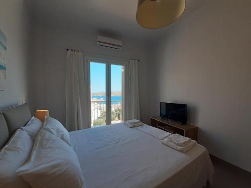 a bedroom with a large white bed and a window at Plakes Luxury Apartments in Ermoupoli