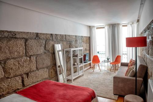 ein Wohnzimmer mit einer Steinmauer, einem Sofa und einem Stuhl in der Unterkunft Try Oporto - Ribeira in Porto
