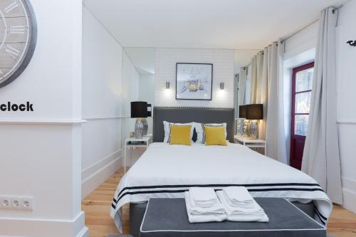 a white bedroom with a large bed with yellow pillows at Loureiro Villas in Porto