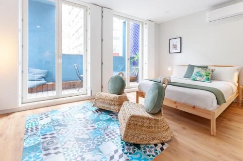 a bedroom with a bed and two chairs and windows at Oporto Palace Apartments in Porto