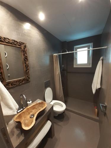 a bathroom with a wooden sink and a toilet at Plakes Luxury Apartments in Ermoupoli