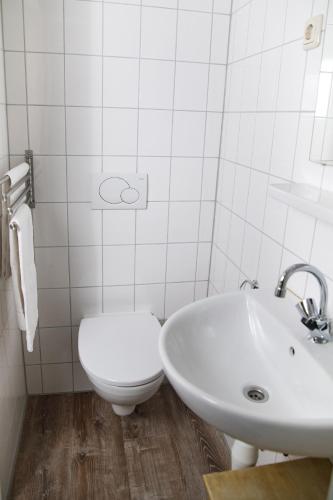 a white bathroom with a toilet and a sink at Hotel Vierhouten in Vierhouten