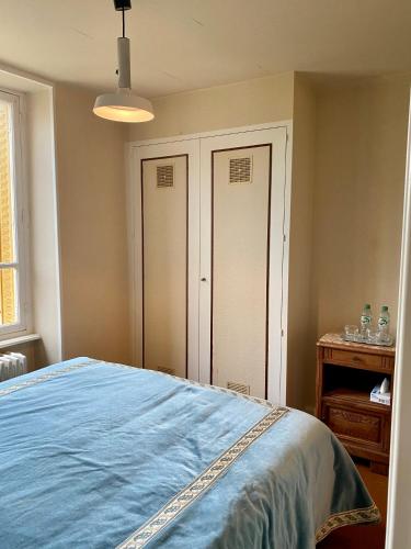 a bedroom with a bed with a blue blanket at Hôtel de famille L.F.M.A.L. in Giat
