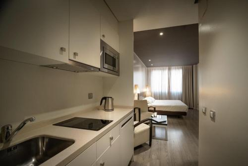 a kitchen with a sink and a living room at Suites Viena Plaza de España in Madrid