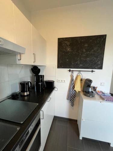 a kitchen with white cabinets and a chalkboard on the wall at An der Wurzel in Germeter