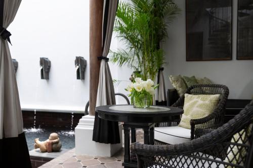 a table with a vase of flowers on a porch at The Siam in Bangkok