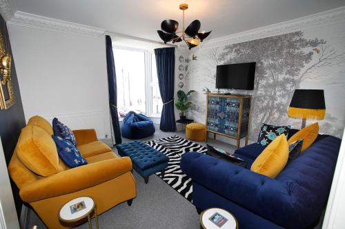 salon z niebieskimi krzesłami i niebieską kanapą w obiekcie Sea Watch Seafront Holiday House w mieście The Mumbles