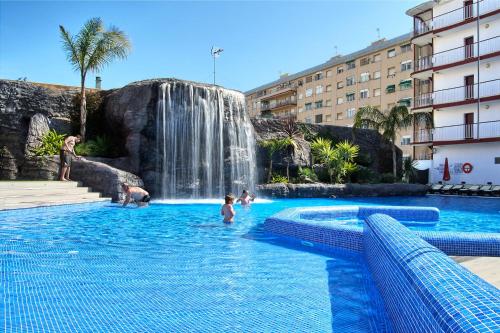 um grupo de pessoas numa piscina com cascata em Hotel Papi Blau em Malgrat de Mar