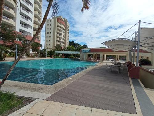 a swimming pool with tables and chairs and buildings at Departamento 4 habitaciones 12 personas vista al mar 8vo piso Playa Almendro in Tonsupa