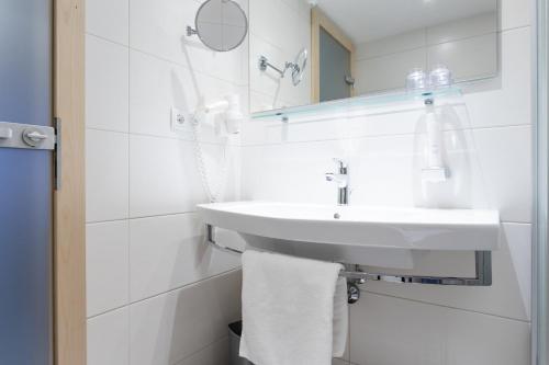 a white bathroom with a sink and a mirror at Landhaus Fiegl in Sölden