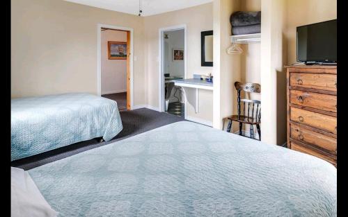 a bedroom with a bed and a dresser and a desk at The Island Inn in Ingonish Beach