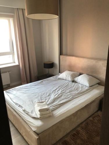 uma cama com lençóis brancos e almofadas num quarto em Luxury Apartments in Platinium Towers em Varsóvia