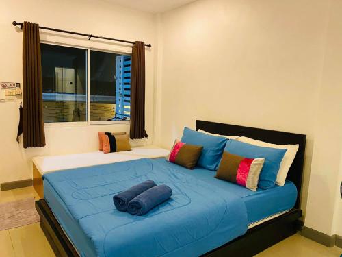 a bedroom with a large blue bed with pillows and a window at Baan Ta Long Beach Koh Larn in Ko Larn