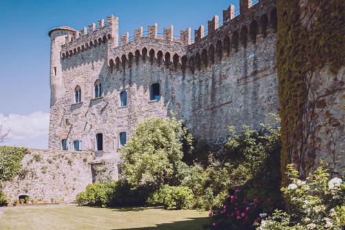 a large stone building with a clock on it's side at Castello di Fosdinovo in Fosdinovo