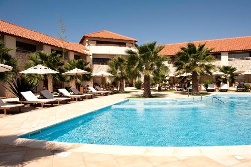 uma piscina num resort com cadeiras e guarda-sóis em Hotel Morabeza em Santa Maria