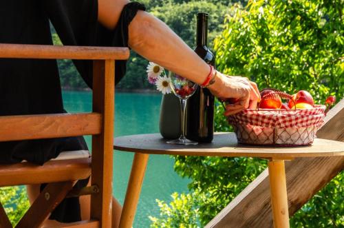 a woman reaching for a glass of wine and a basket of fruit at Piva Lake Glamping in Pluzine