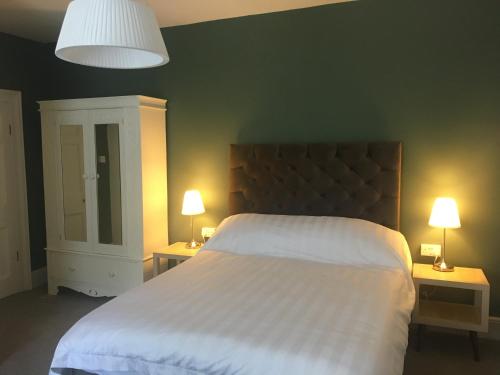 a bedroom with a large white bed with two lamps at Kings B&B in South Molton