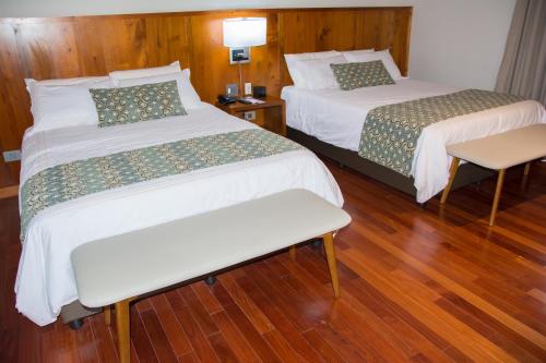 two beds in a hotel room with wooden floors at Los Brezos Hotel Boutique in Volcán