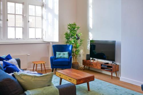 a living room with a blue chair and a tv at GuestReady - Sophisticated Home in Shoreditch in London