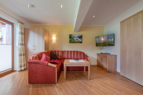 a living room with a red couch and a table at Haus Rosmarie in Neustift im Stubaital