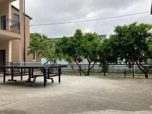 a ping pong table in front of a building with trees at Karina in Gagra