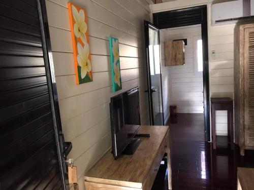a living room with a tv and a wooden table at La Perle Tahaa in Tapu' amu