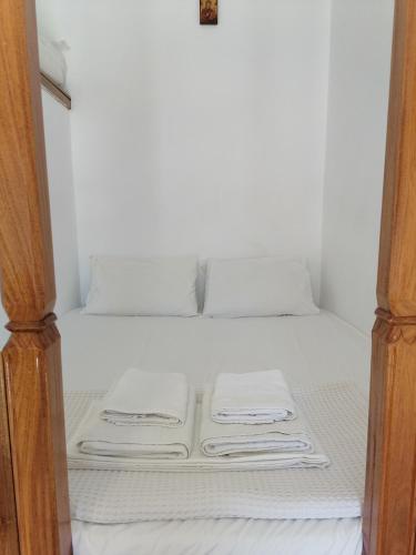 een bed met witte lakens en opvouwbare handdoeken bij KALLIOPIS STUDIO in Olympos