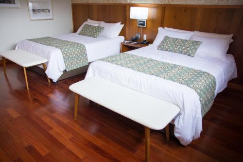 a hotel room with two beds and a bench at Los Brezos Hotel Boutique in Volcán