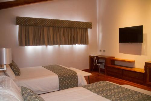 a hotel room with two beds and a flat screen tv at Los Brezos Hotel Boutique in Volcán