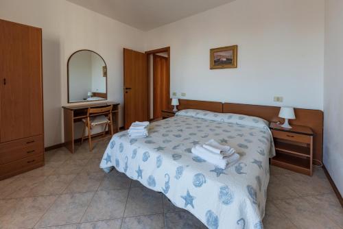 a bedroom with a bed and a desk and a mirror at Residenza Nobel Appartamenti in Rimini