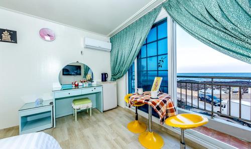 een slaapkamer met een bureau en uitzicht op de oceaan bij Jeju Sea Palace Pension in Jeju-stad