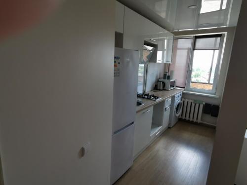 a white kitchen with a sink and a stove at Saulėlydžio Apartamentai in Panevėžys