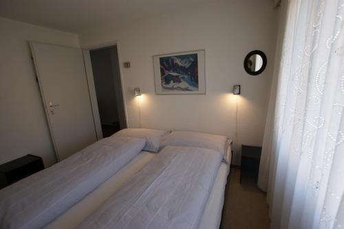 two beds in a small bedroom with a window at Valbella in Davos