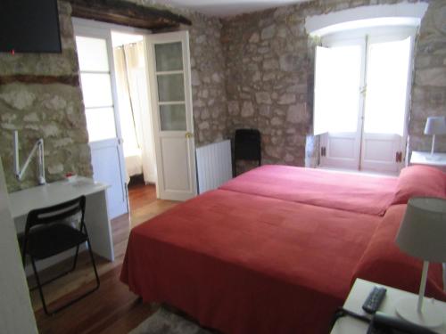 a bedroom with a red bed and a desk and windows at HOSTERÍA SEÑORÍO DE BIZKAIA in Bakio