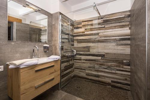 Saint-Jacques-en-ValgodemardにあるChambres d'hotes Les Clarinesのバスルーム(木製の洗面化粧台、ガラス張りのシャワー付)