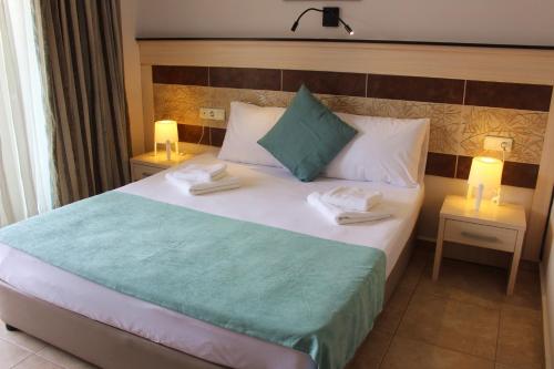 a bedroom with a large bed with two lamps on it at Avlu Hotel in Kemer