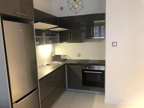 a kitchen with black cabinets and a sink at Apartament Noniewicza 95 in Suwałki