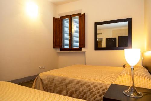 a bedroom with a bed with a mirror and a lamp at Villa Montarioso in Siena