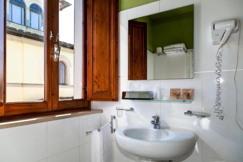 a white bathroom with a sink and a mirror at Villa Montarioso in Siena